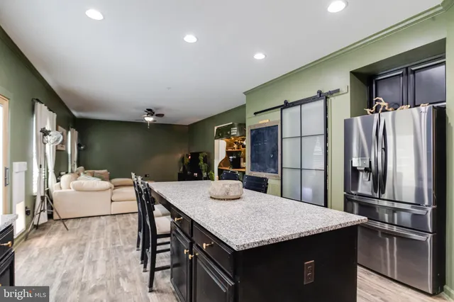 a kitchen with stainless steel appliances granite countertop a refrigerator a stove top oven a dining table and chairs