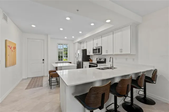 a kitchen with appliances a table and chairs in it