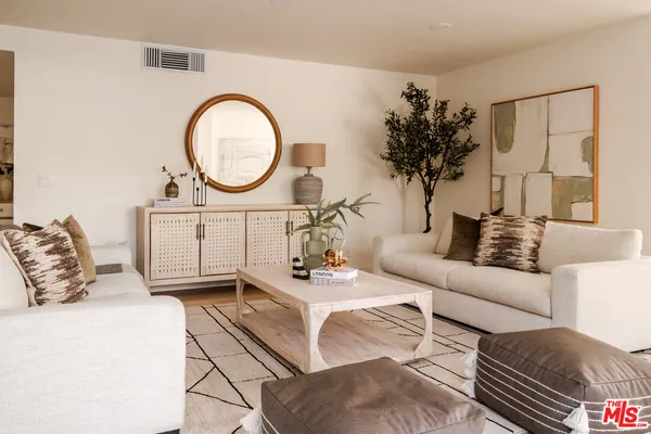 a living room with furniture a mirror and a potted plant