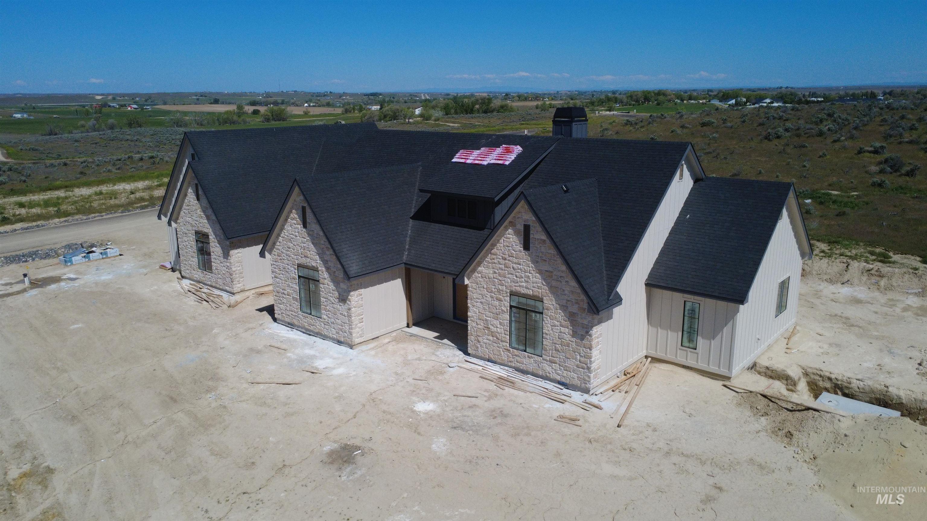 27502 Commerce Comet Way Caldwell, ID 83607 - Photo 3 of 8 Exterior featuring a multi-textured facade with stone accents and vertical siding, a dark shingle roof, and multiple gables