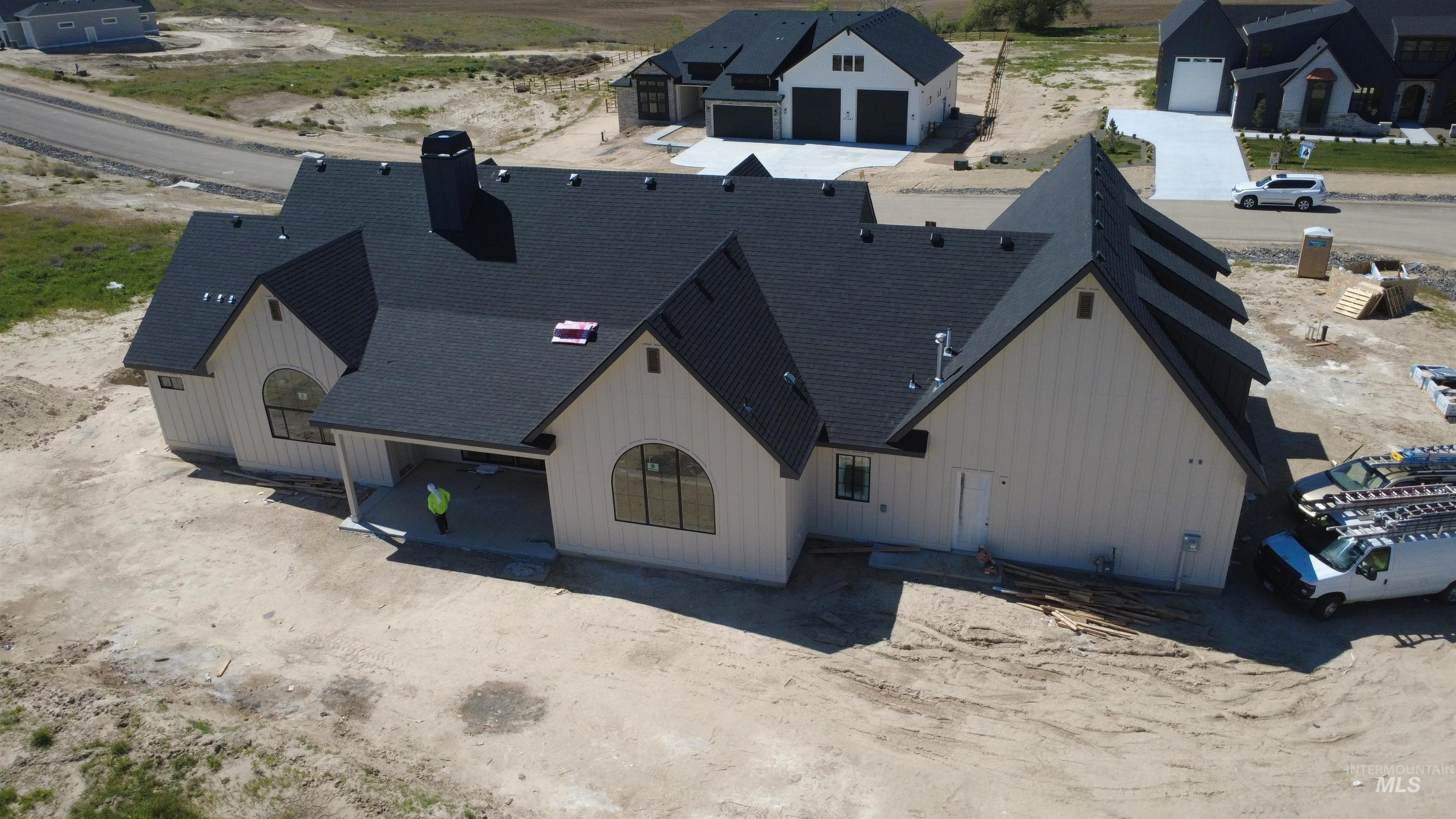 27502 Commerce Comet Way Caldwell, ID 83607 - Photo 5 of 8 Modern farmhouse exterior featuring an arched window, board and batten siding, dark shingle roof, and an attached covered patio