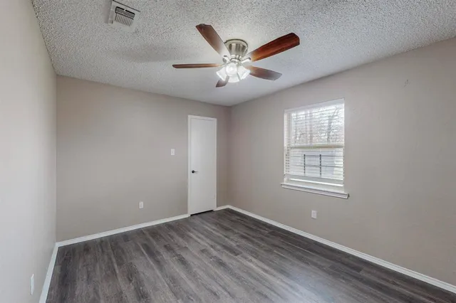 an empty room with wooden floor ceiling fan and windows