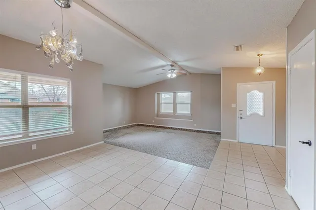 an empty room with chandelier and windows