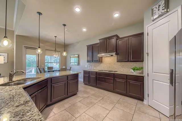 a large kitchen with kitchen island granite countertop a sink a counter space appliances and cabinets