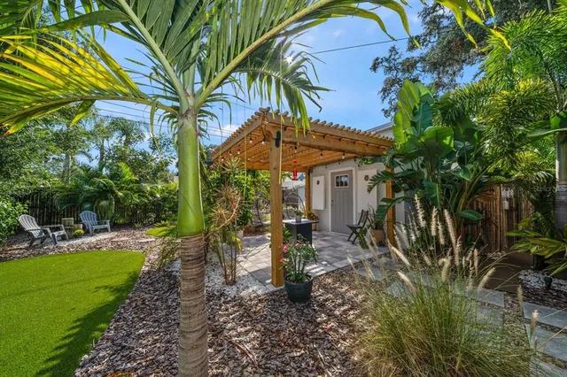 a view of a patio with table and chairs potted plants and large tree