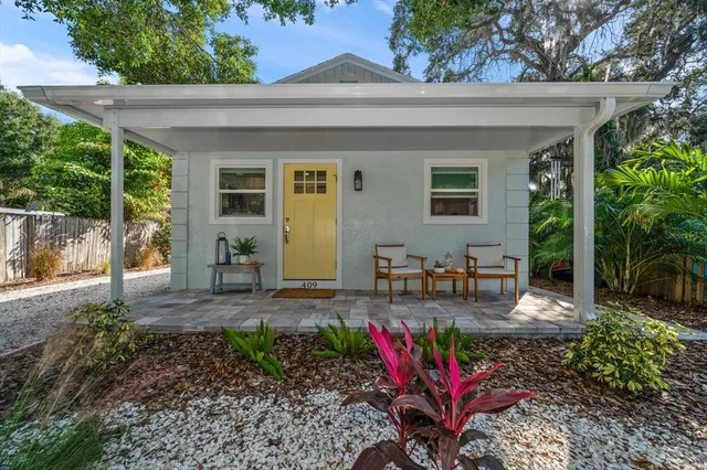 a view of a patio with table and chairs potted plants and large tree