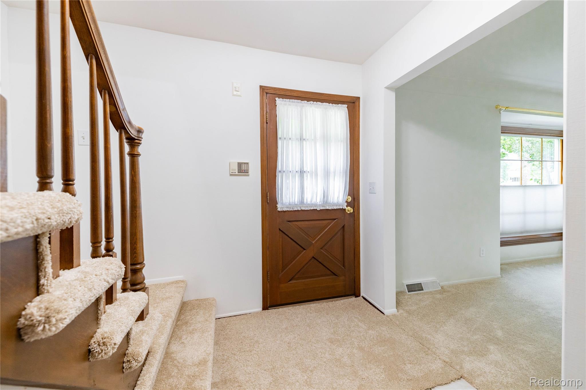 7611 Ferry Road Grosse Ile, MI 48138 - Photo 11 of 51 Entryway featuring a wood-panel door with glass inserts, a carpeted staircase with a wood balustrade, and light-toned wall finishes