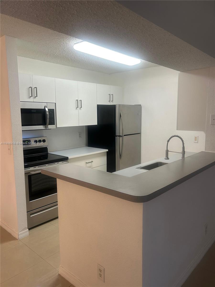 3995 West McNab Road, Unit B310 Pompano Beach, FL 33069 - Photo 5 of 10 a kitchen with stainless steel appliances a refrigerator sink and white stove