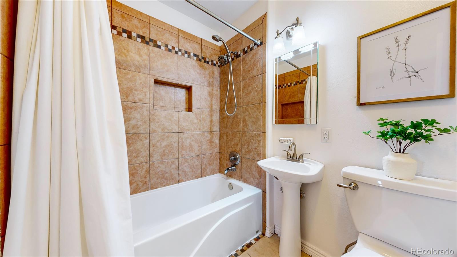 3246 South Stuart Street Denver, CO 80236 - Photo 19 of 43 a bathroom with a sink a toilet a shower curtain and a bath tub