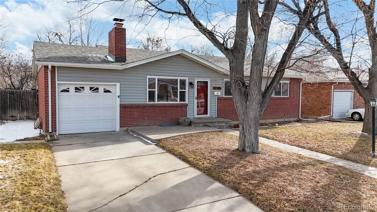 3246 South Stuart Street Denver, CO 80236 - Photo 4 of 43 a front view of a house with a yard and large tree