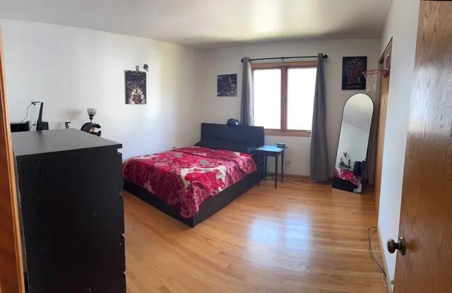 a bedroom with a bed wooden floor and a window