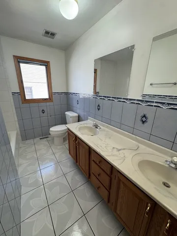 a spacious bathroom with a double vanity sink a mirror and a toilet