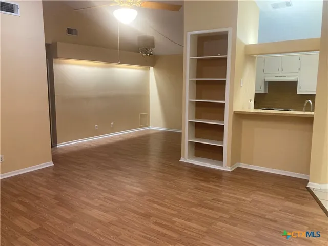 a view of an empty room with a fireplace and wooden floor