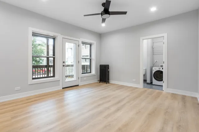 a view of an empty room with a window and wooden floor
