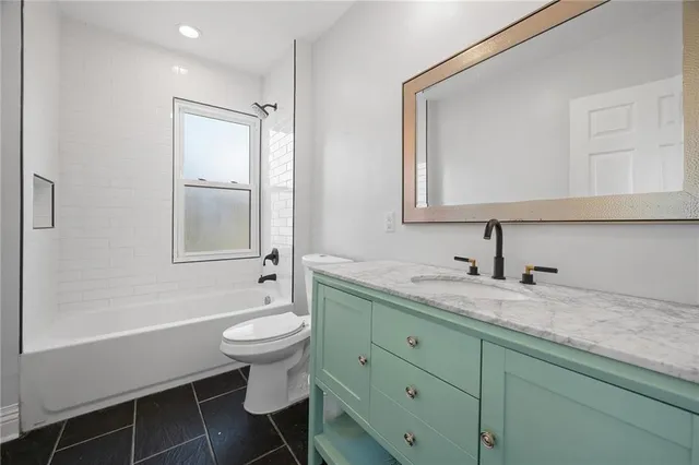 a bathroom with a granite countertop sink toilet and mirror