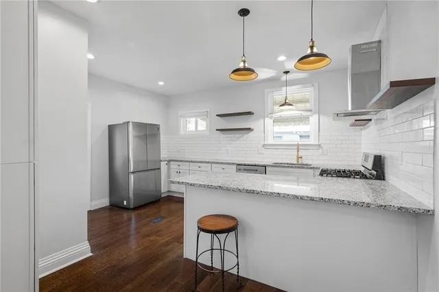 a kitchen with stainless steel appliances granite countertop a sink a stove and a wooden floors