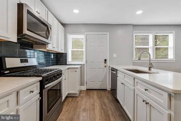 a kitchen with granite countertop a sink a stove top oven and cabinetry
