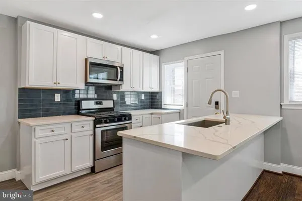 a kitchen with stainless steel appliances granite countertop a sink and white cabinets
