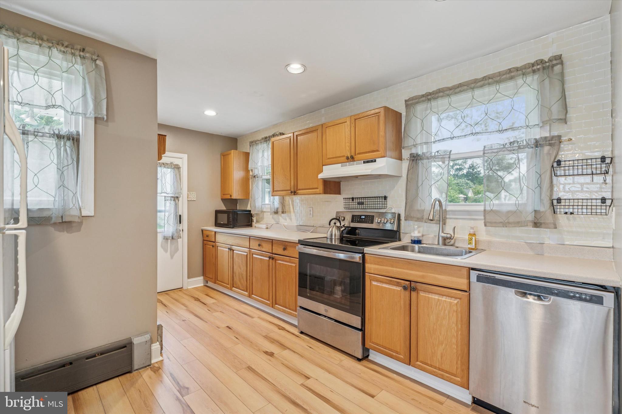 633 East Manoa Road Havertown, PA 19083 - Photo 15 of 25 a kitchen with stainless steel appliances granite countertop a stove a sink dishwasher and a refrigerator with wooden floor