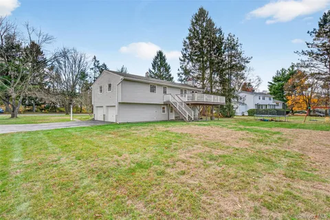 a view of a house with a big yard and large trees