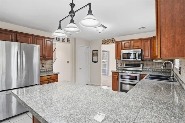 a kitchen with stainless steel appliances granite countertop a refrigerator and a stove top oven