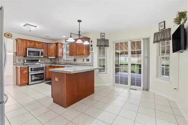 a kitchen with stainless steel appliances granite countertop a stove top oven a sink dishwasher a dining table and chairs with wooden floor