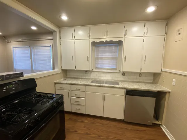 a kitchen with kitchen island granite countertop wooden cabinets and a stove