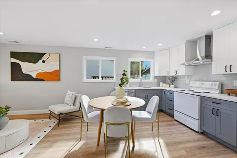 a kitchen with a dining table chairs wooden floor and appliances