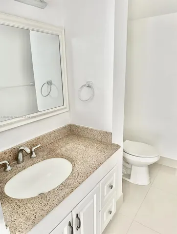 a bathroom with a granite countertop sink a toilet and a mirror