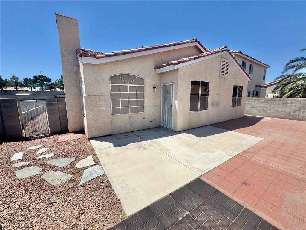 7340 Ridge Star Court Las Vegas, NV 89131 - Photo 22 of 22 A compact stucco building features a tiled roof and a blend of concrete and brick paver patio spaces.