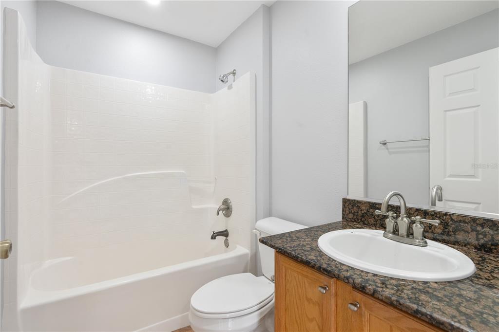 17168 Southwest 39th Circle Ocala, FL 34473 - Photo 20 of 36 a bathroom with a granite countertop sink a toilet a mirror a bathtub and shower