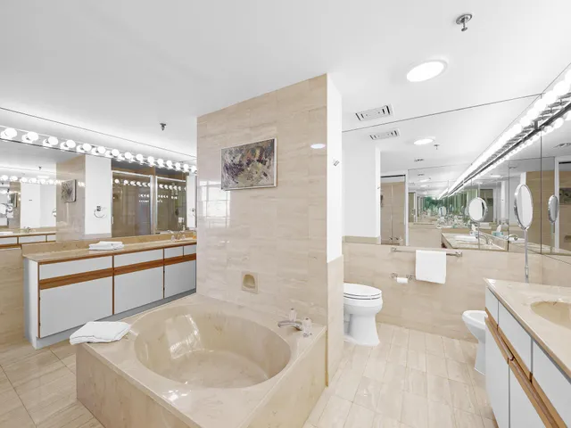 a large white bathroom with a granite countertop tub a sink and a large mirror