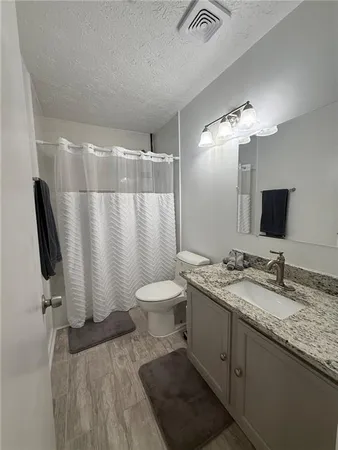 a bathroom with a granite countertop sink toilet and mirror