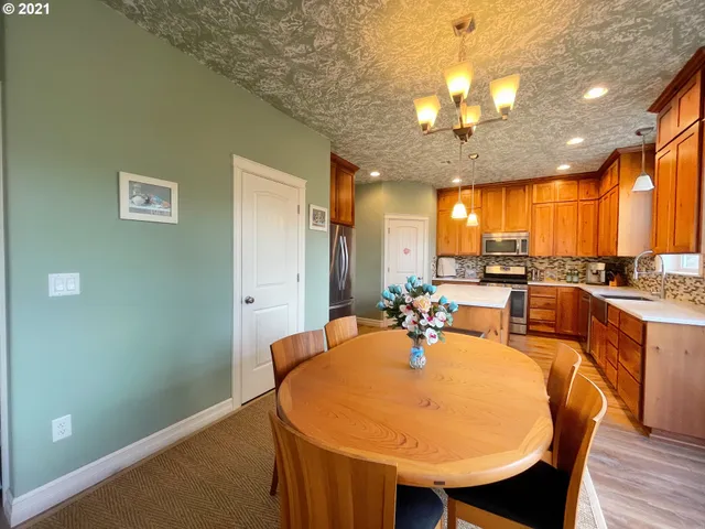 a dining room with wooden floor a chandelier a wooden table and chairs