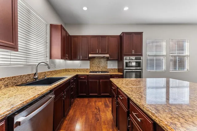a kitchen with granite countertop stainless steel appliances window a sink and a counter space