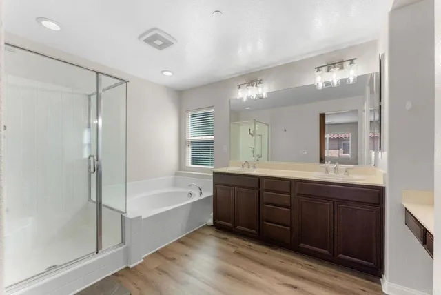 a bathroom with a tub sink shower and two mirror