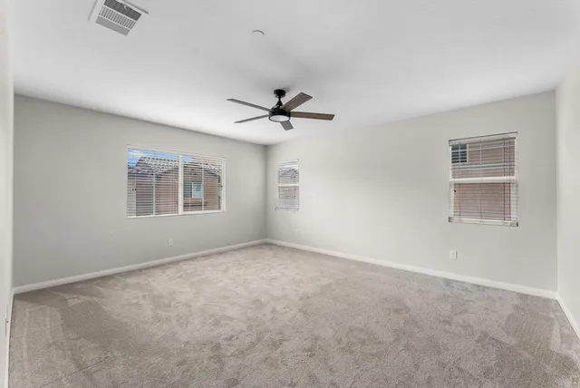 an empty room with windows and ceiling fan