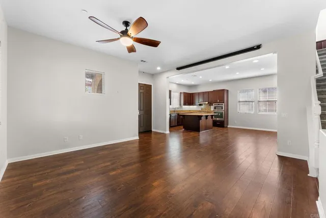 a view of empty room with wooden floor and ceiling fan