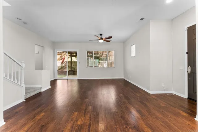 an empty room with wooden floor windows and ceiling fan