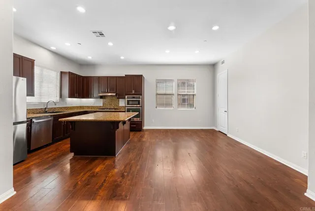 a kitchen with stainless steel appliances granite countertop a refrigerator a stove top oven a sink dishwasher and wooden floor