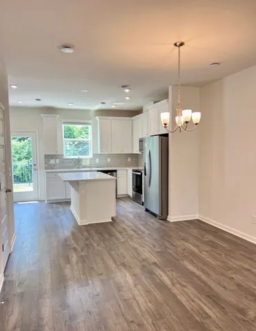 a large kitchen with kitchen island a island a stove a refrigerator and a wooden floor