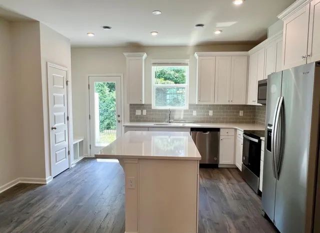 a kitchen with stainless steel appliances granite countertop a refrigerator a sink dishwasher a stove with wooden floor