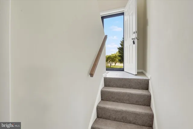 a view of staircase with white walls and white door