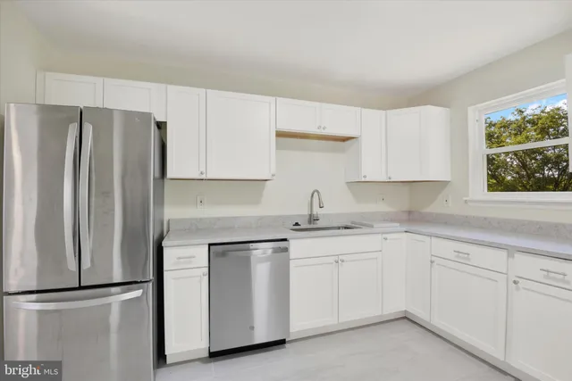 a kitchen with white cabinets sink and refrigerator