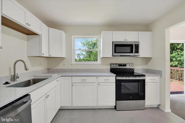 a kitchen with white cabinets stainless steel appliances and window