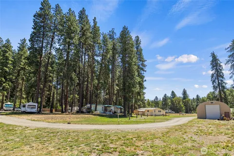 a view of a house with large tree and wooden fence