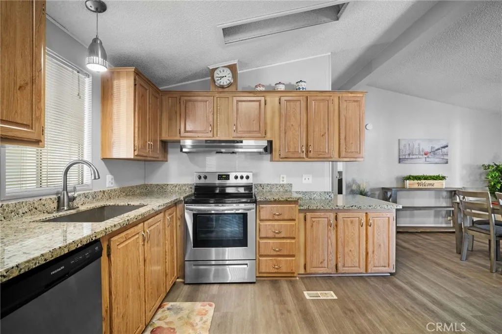 27701 Murrieta Road, Unit 37 Menifee, CA 92586 - Photo 10 of 24 a kitchen with stainless steel appliances granite countertop wooden cabinets a stove a sink and dishwasher with wooden floor
