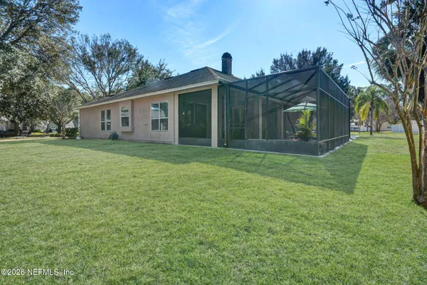 a view of a yard in front of a house with large trees