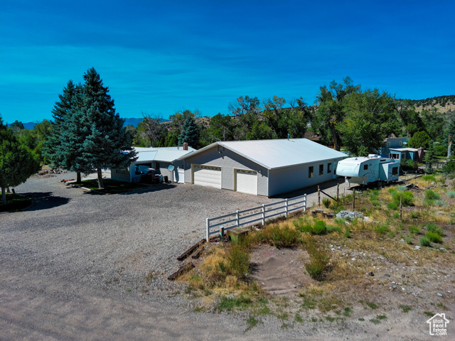 View of front facade with a garage, a metal roof, and driveway