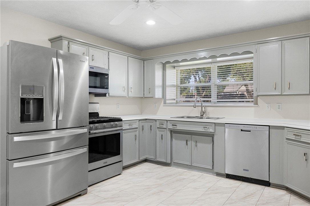 1906 Gun And Rod Road Brenham, TX 77833 - Photo 18 of 30 Kitchen featuring stainless steel appliances, gray cabinets, light countertops, a ceiling fan, and light marble finish flooring